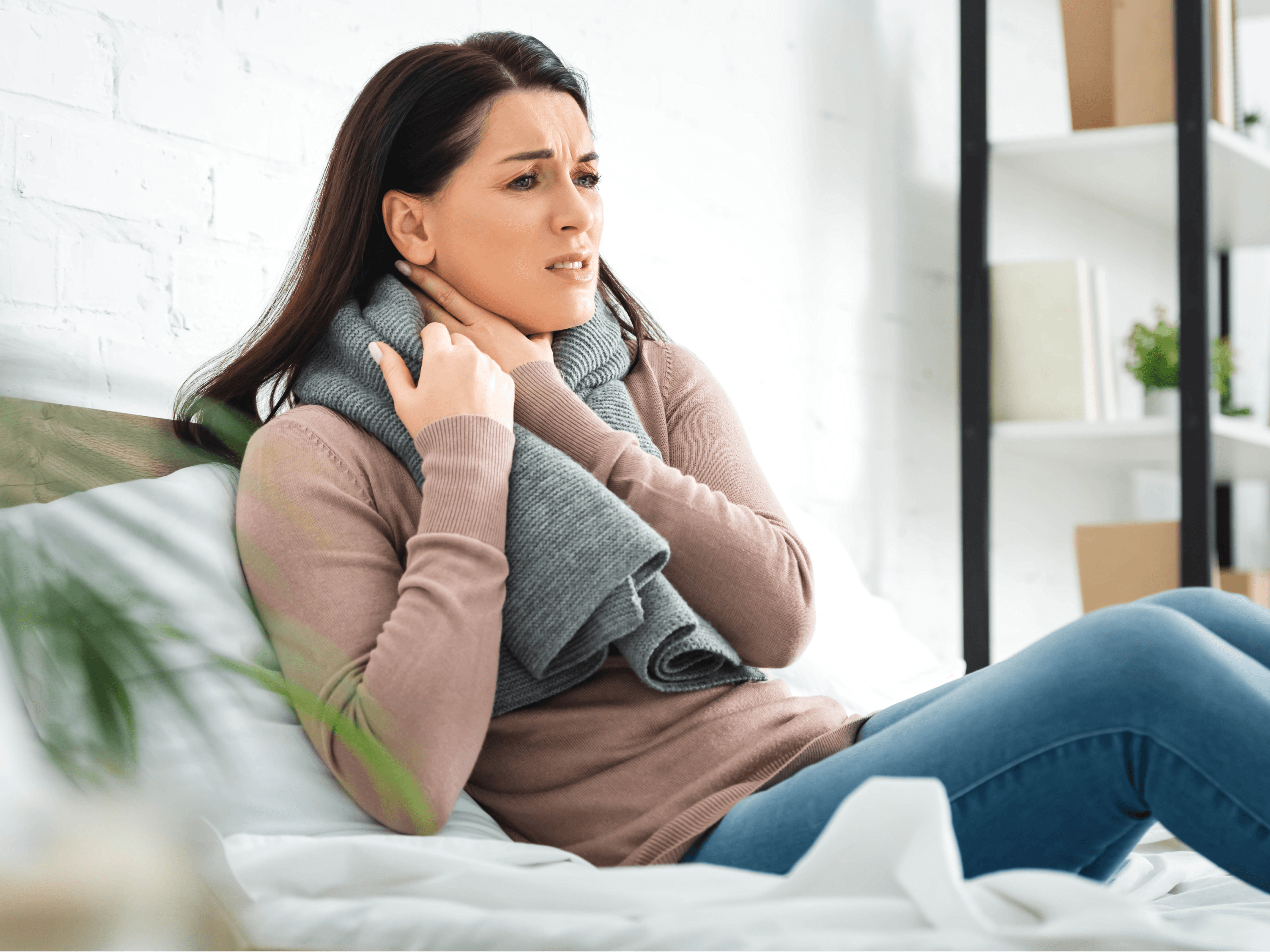 Mulher com dor na garganta e expressão de desconforto, possível sintoma da fibromialgia.