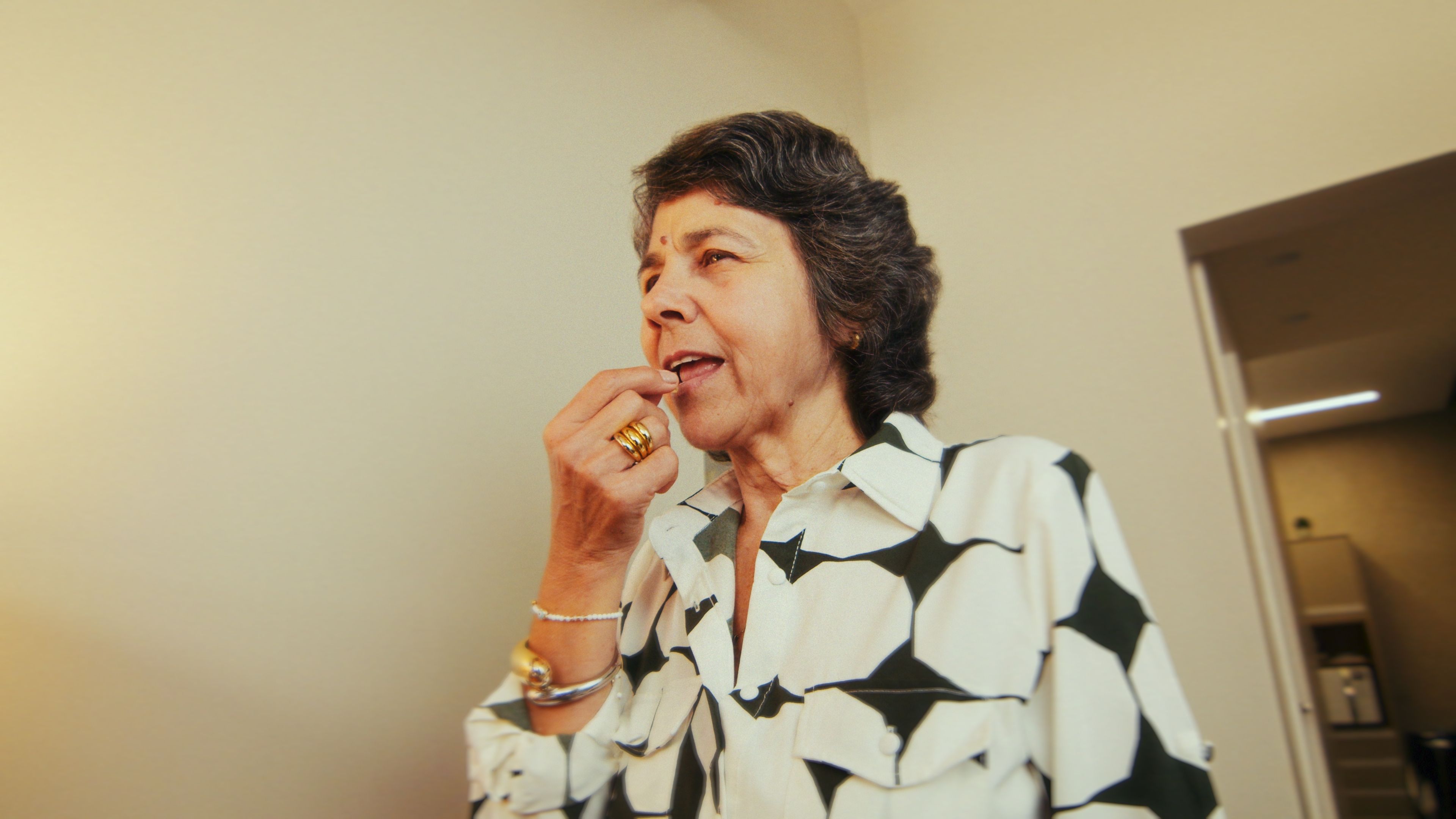 Mulher madura colocando gummy na boca, representando o uso de tratamento com cannabis medicinal.