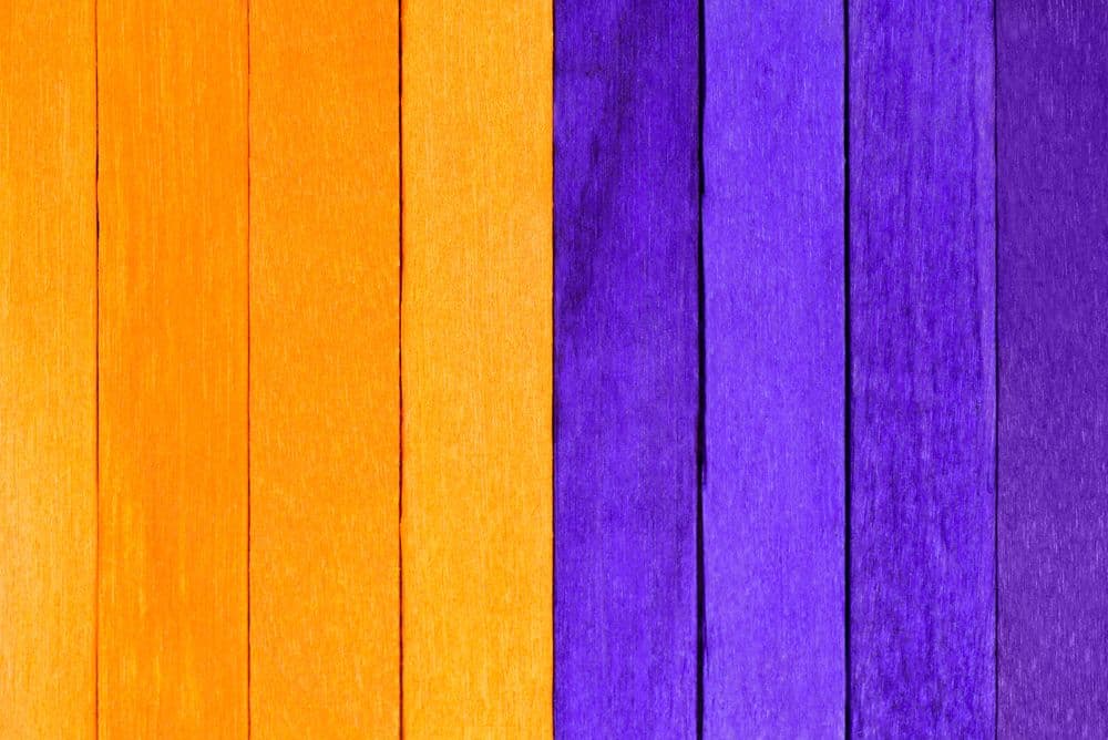 Textura de madeira com faixas laranja e roxas simbolizando a campanha Fevereiro Roxo e Laranja.