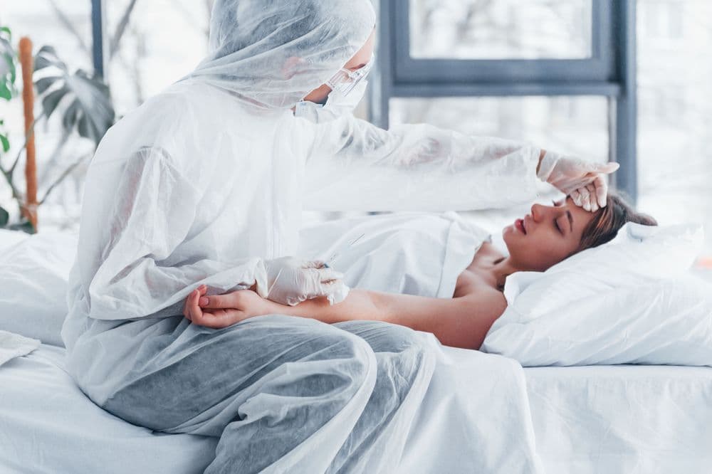 Médico em equipamento de proteção trata paciente doente com Canabidiol (CBD) em ambiente hospitalar.