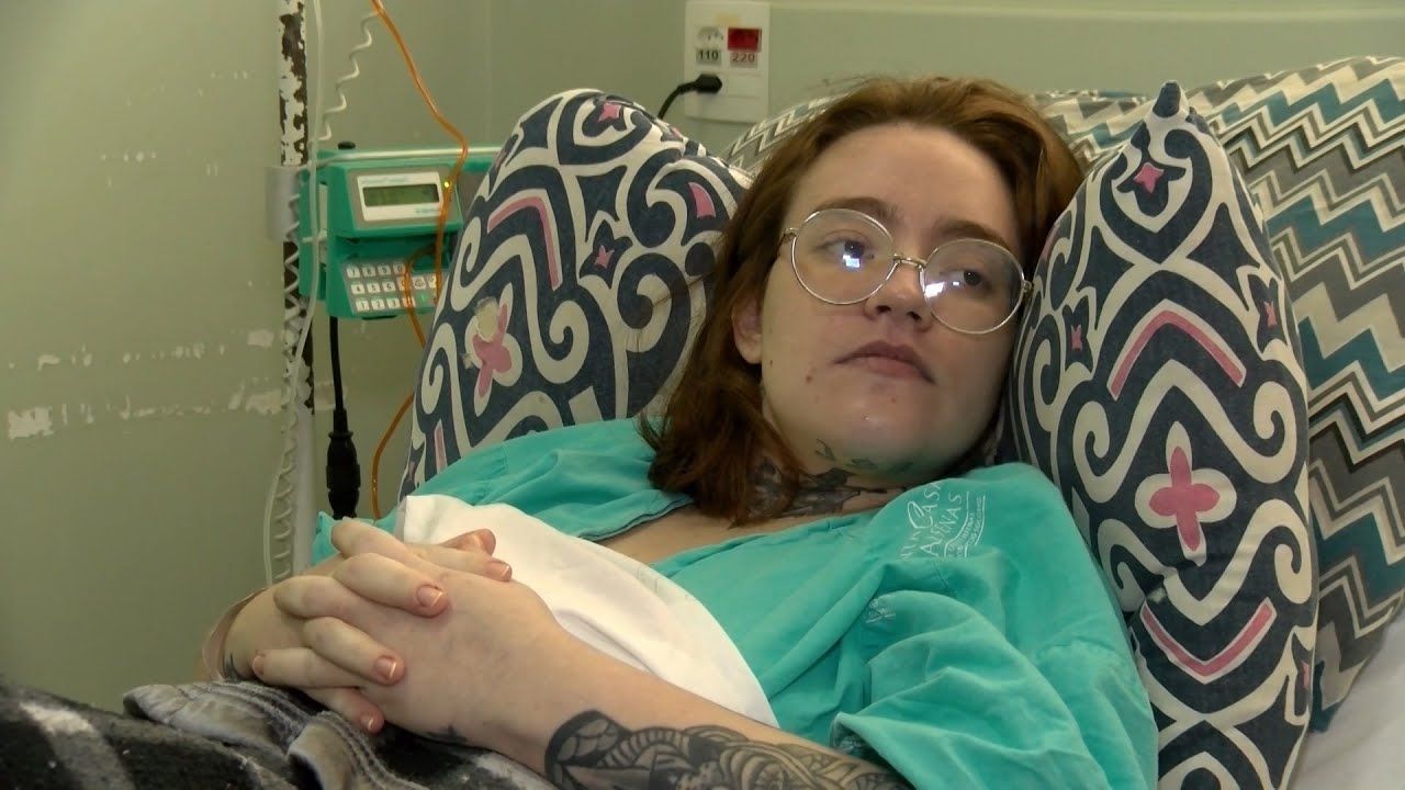 Carolina Arruda, vestindo avental hospitalar, em hospital.