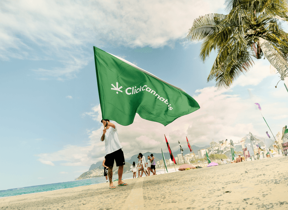 Foto da bandeira da Click Cannabis na praia do Arpoador no Rio de Janeiro, durante o evento de limpeza de praia.