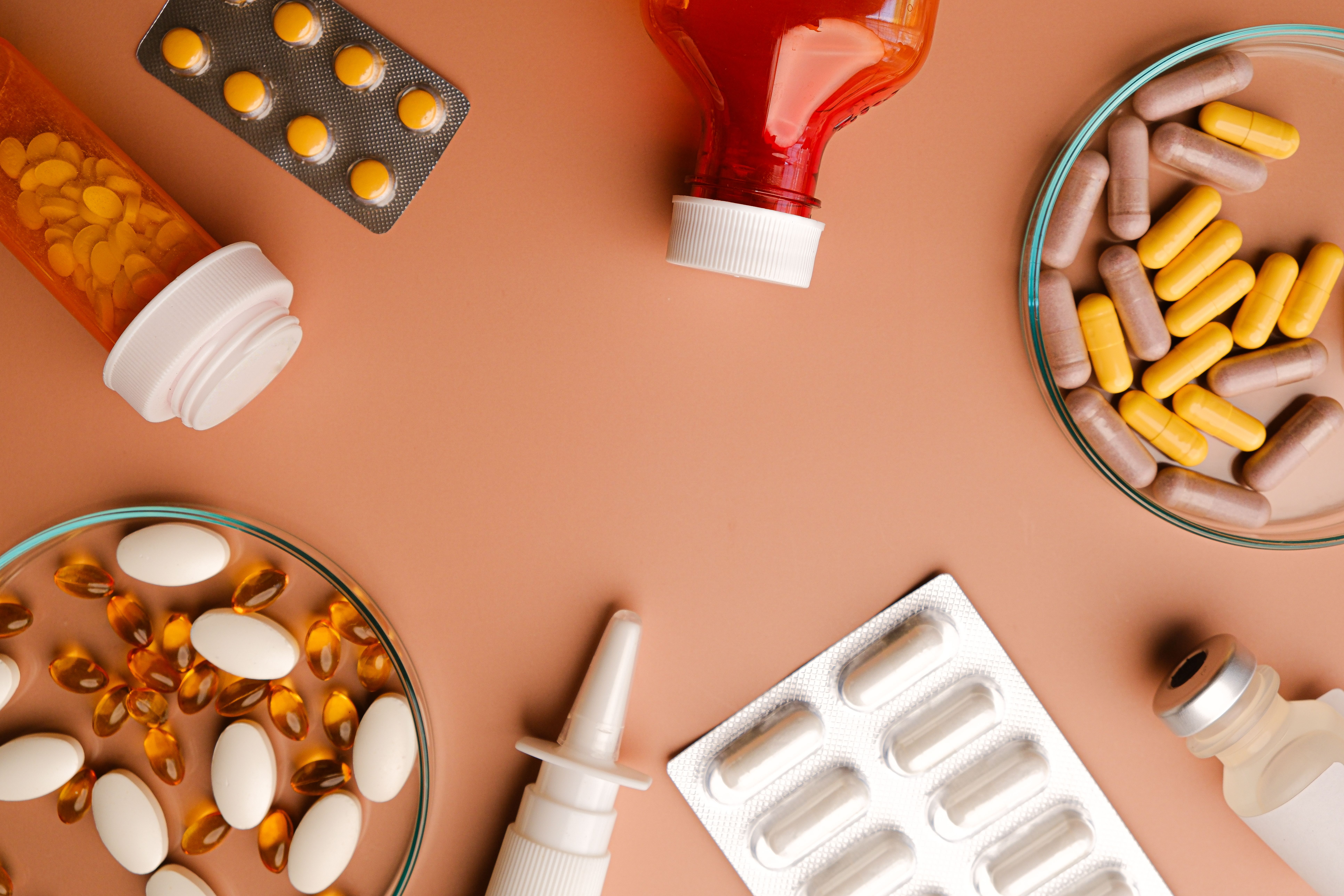 Diferentes formas farmacêuticas de medicamentos sobre uma superfície de tom bege.