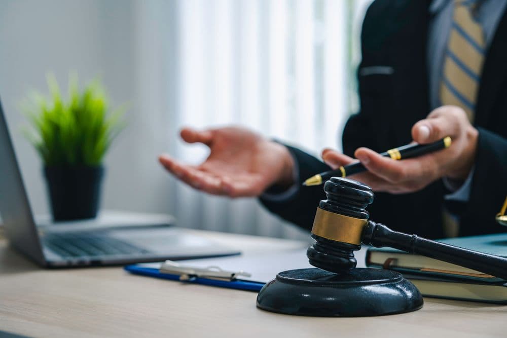 Advogado explica direitos de pacientes que utilizam cannabis medicinal no Brasil, com martelo da justiça sobre a mesa e laptop ao fundo.