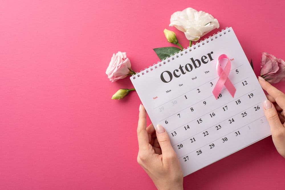 Calendário de outubro com laço rosa e flores, símbolo da campanha Outubro Rosa de conscientização sobre o câncer de mama.