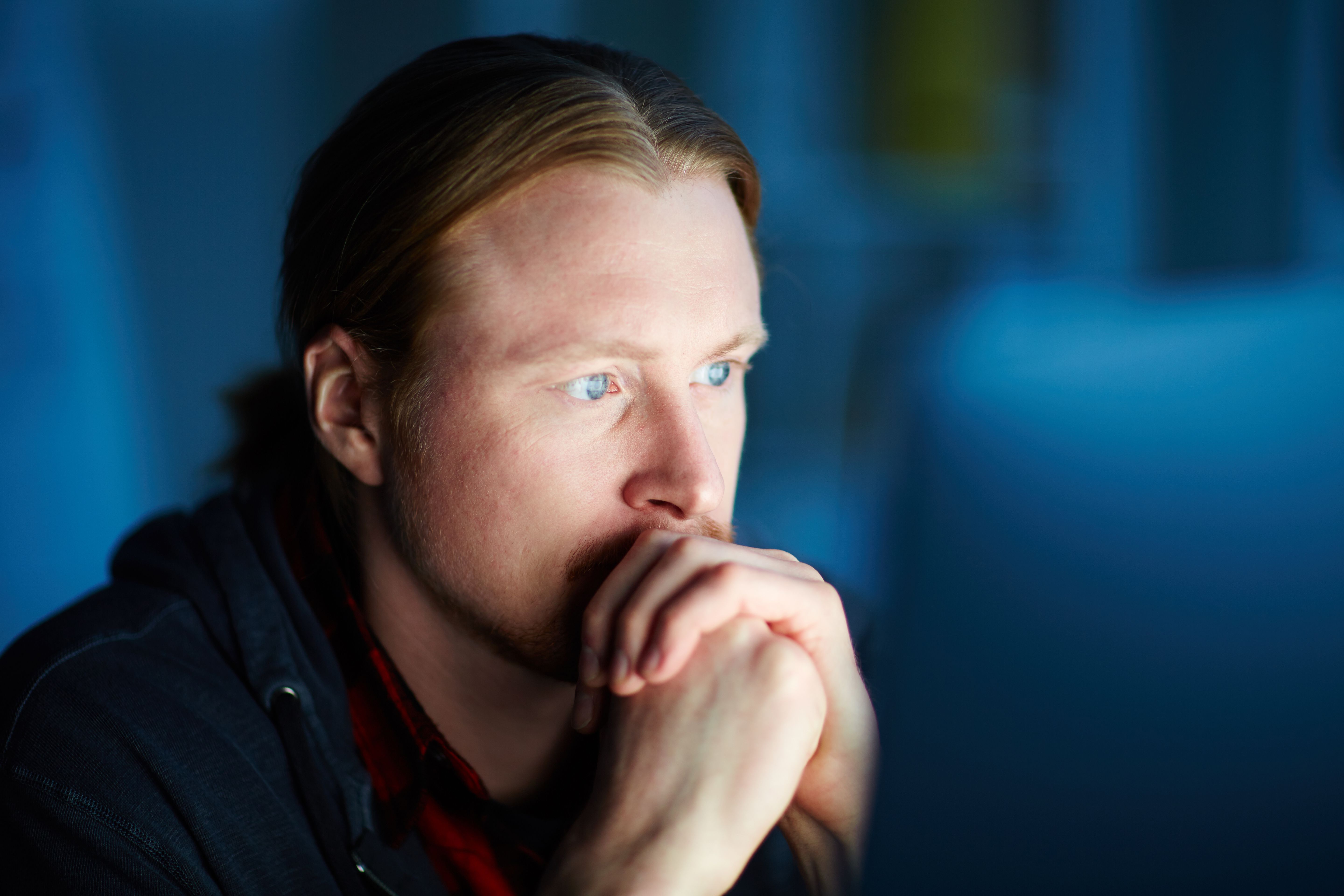 Homem pensativo olhando para frente, representando preocupações com desempenho sexual e saúde hormonal