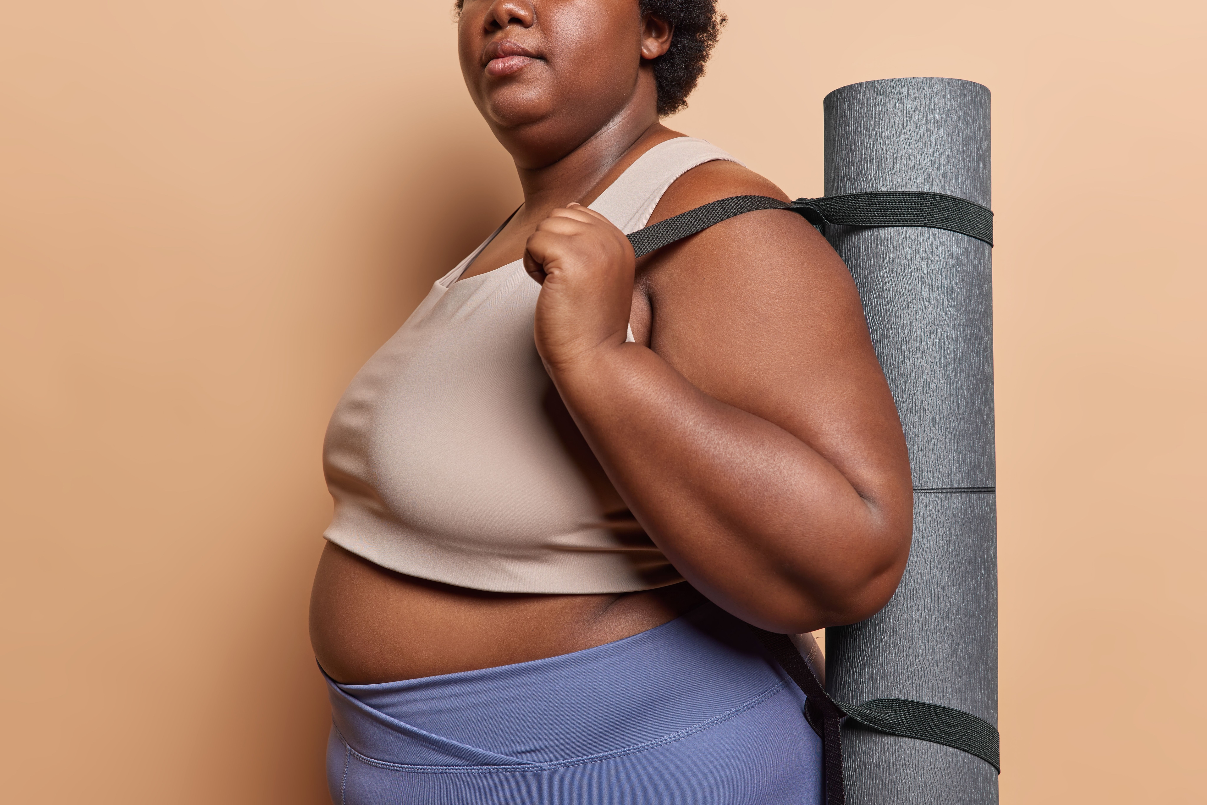 Mulher plus size com tapete de yoga nas costas