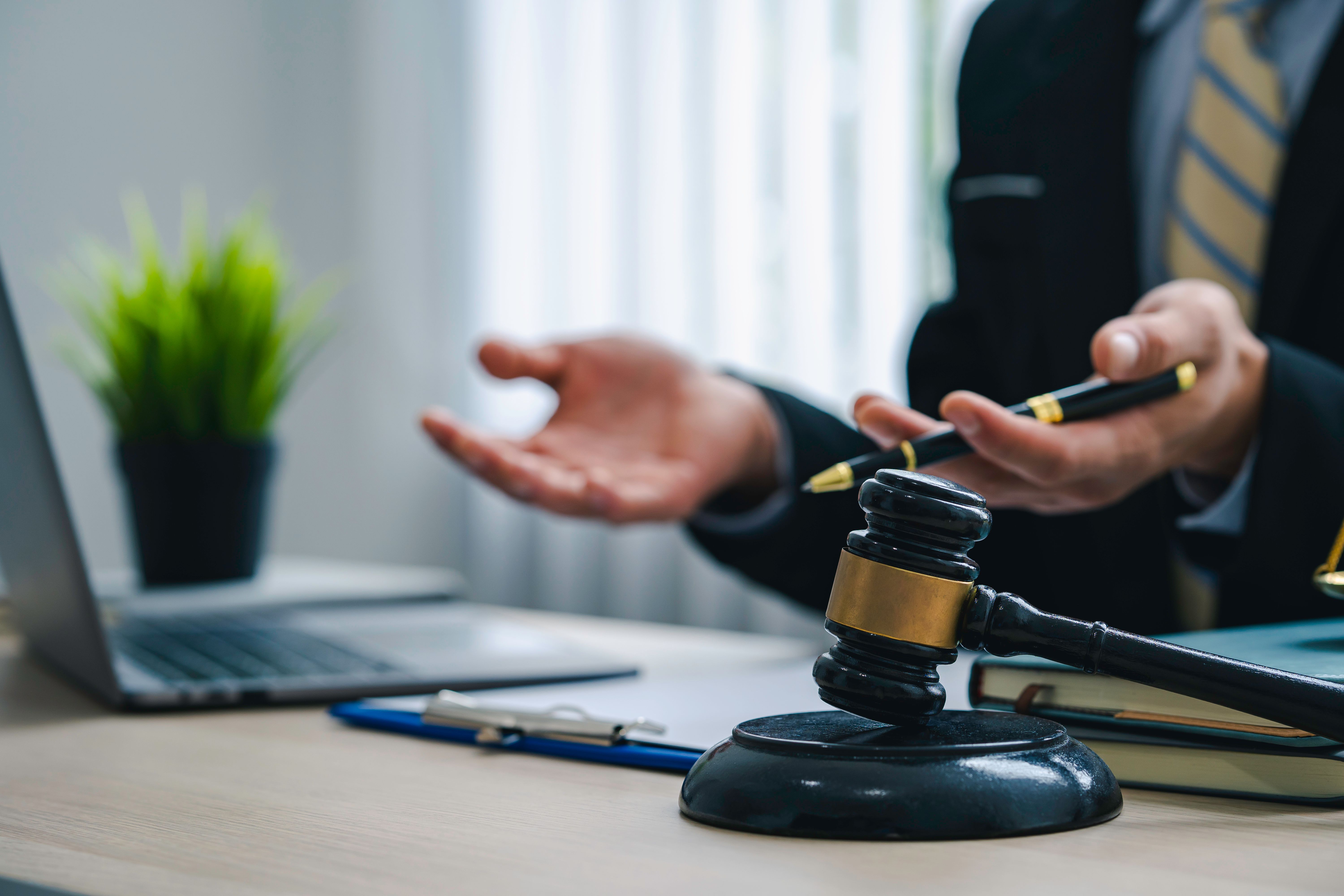 Advogado explica direitos de pacientes que utilizam cannabis medicinal no Brasil, com martelo da justiça sobre a mesa e laptop ao fundo.