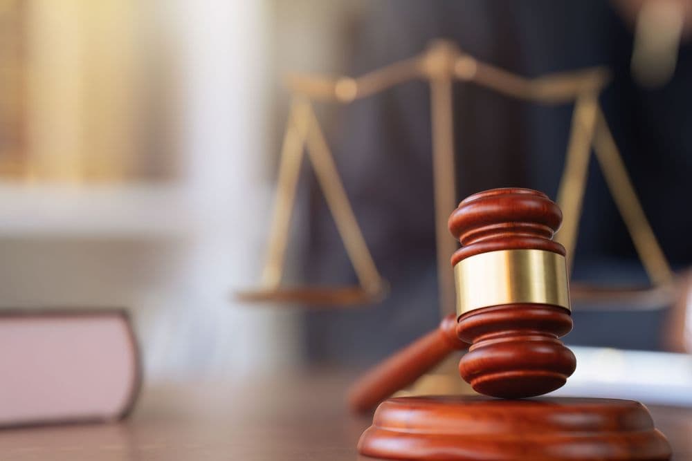 Martelo de juiz e balança da justiça representando os desafios legais da cannabis medicinal no Brasil.